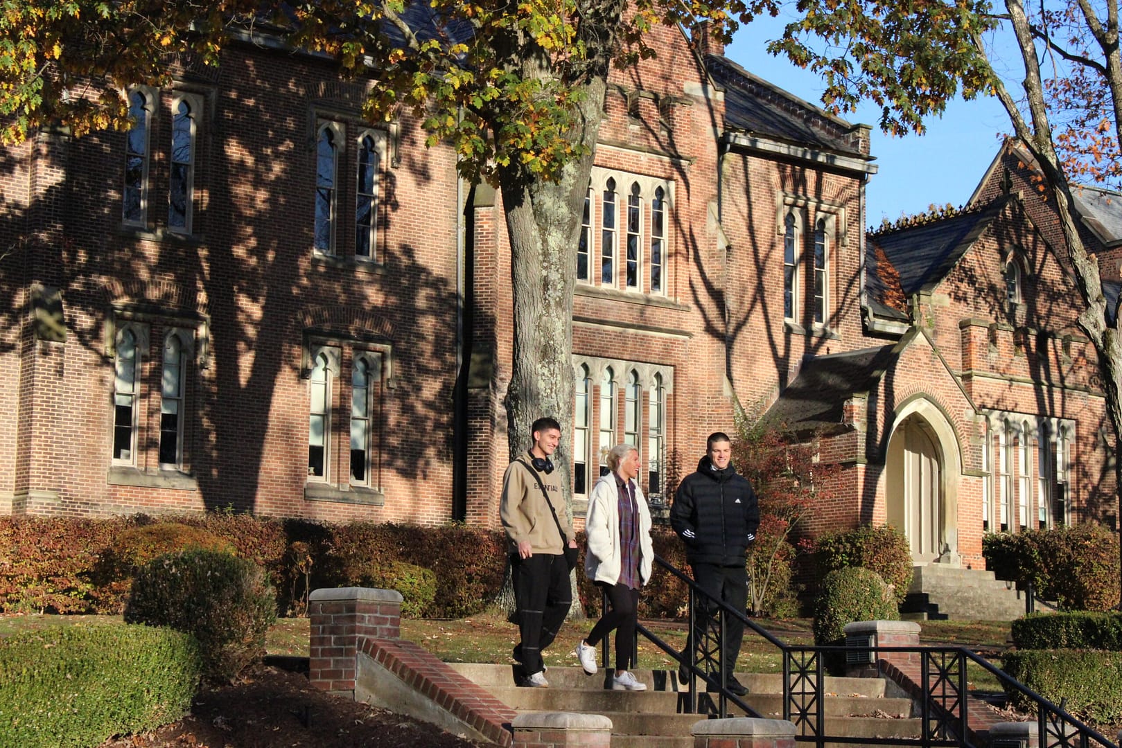 Two boys and one girl student walking down stairs to fountain from Old Main