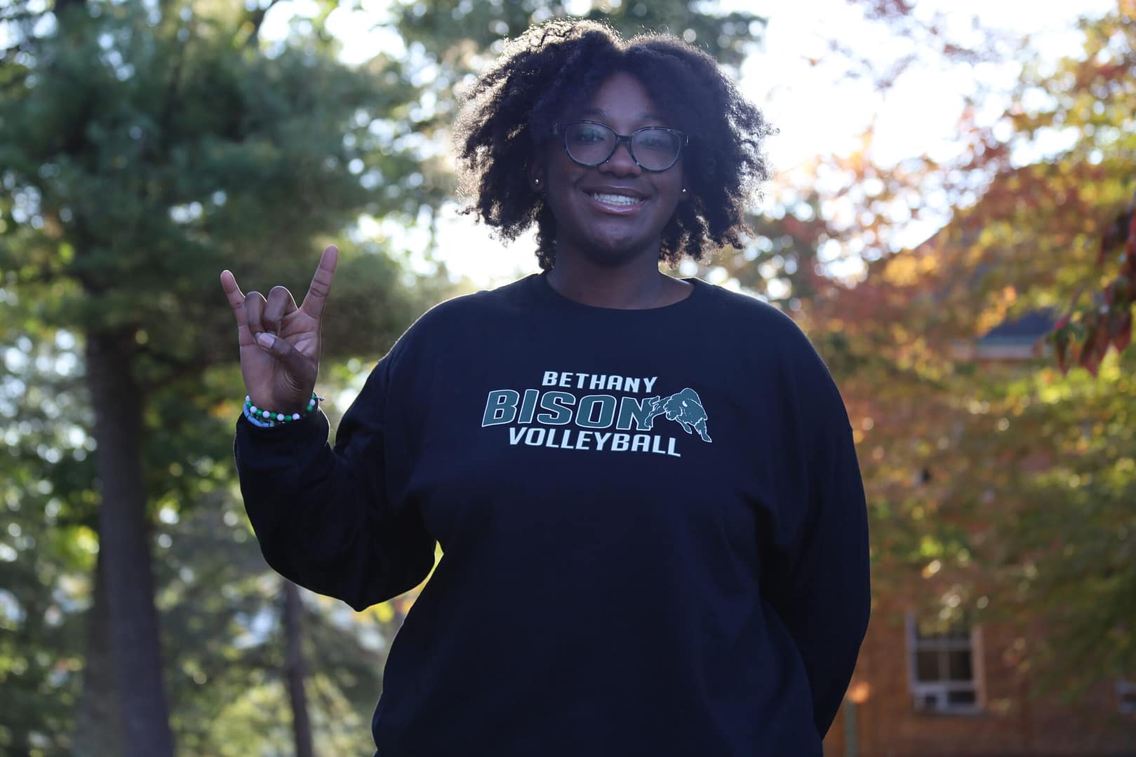 Student holding up a Roll Bison sign and smiling at the camera